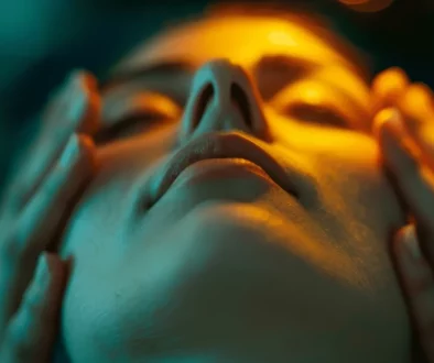 Femme en séance d’hypnose à Lausanne, visage apaisé, lumière douce symbolisant le lien entre la peau, les émotions et le bien-être.